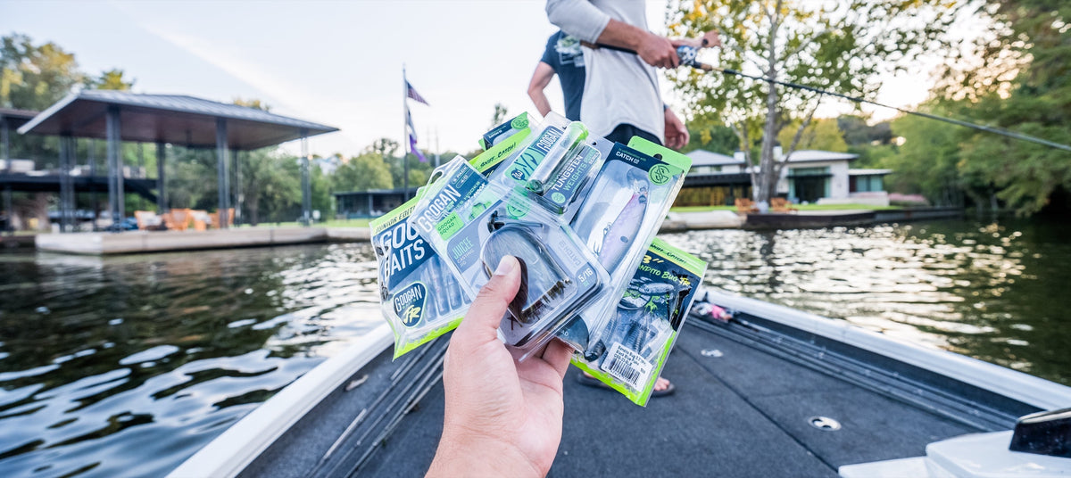 Angler holding a stack of Googan bait packs on a bass boat