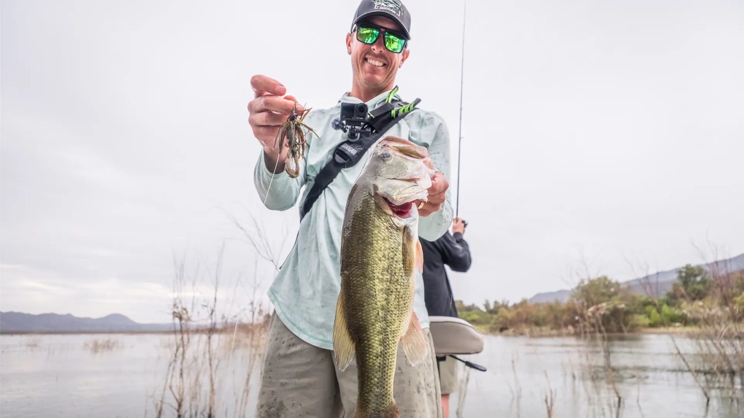 Angler displaying a pre-spawn bass caught on a jig near cover.