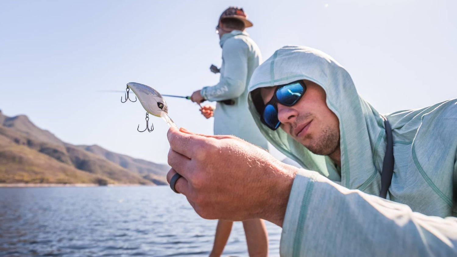 Angler holding squarebill crankbait lure on boat in bright sun