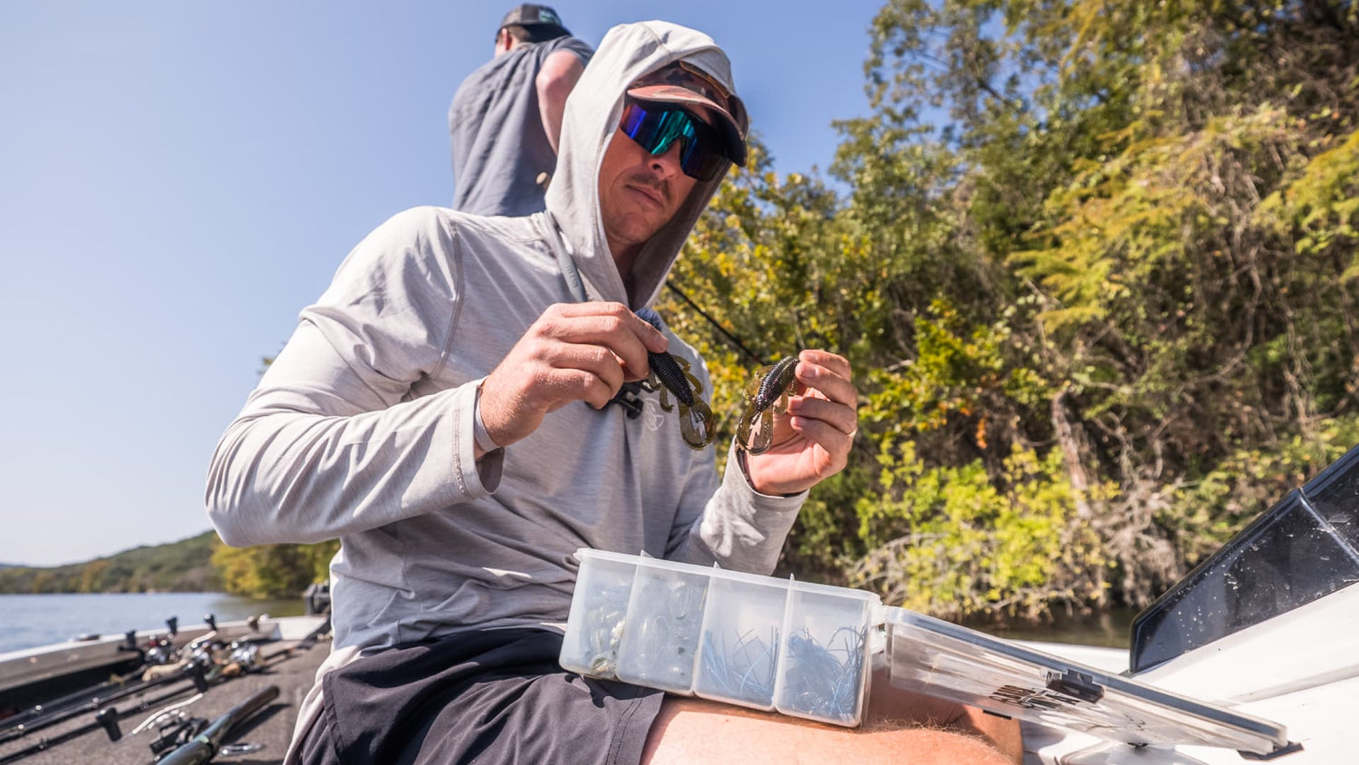 Angler sorting bass lures in tackle box on boat before fishing