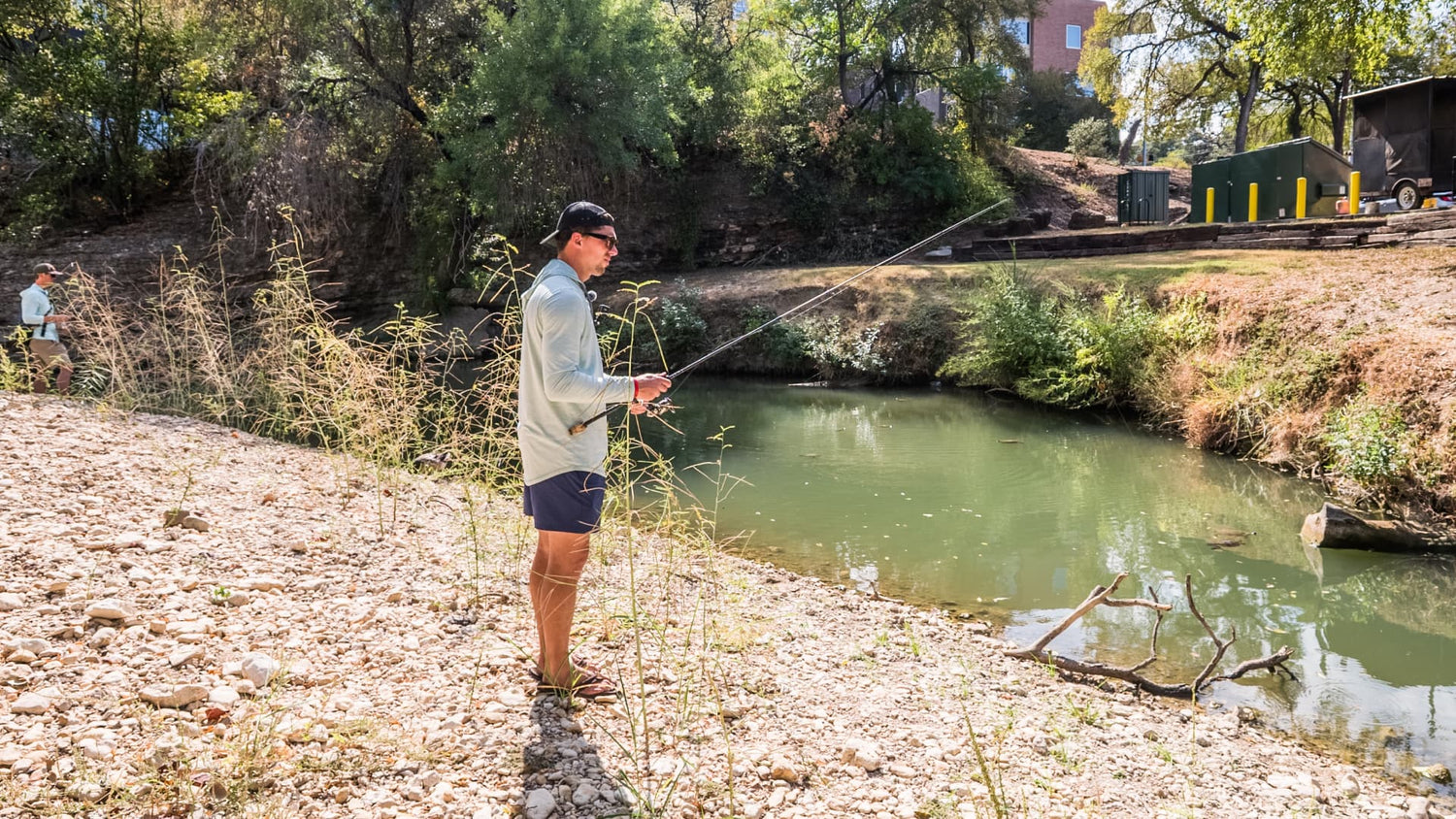 Angler reading creek water and fishing for bass near cover