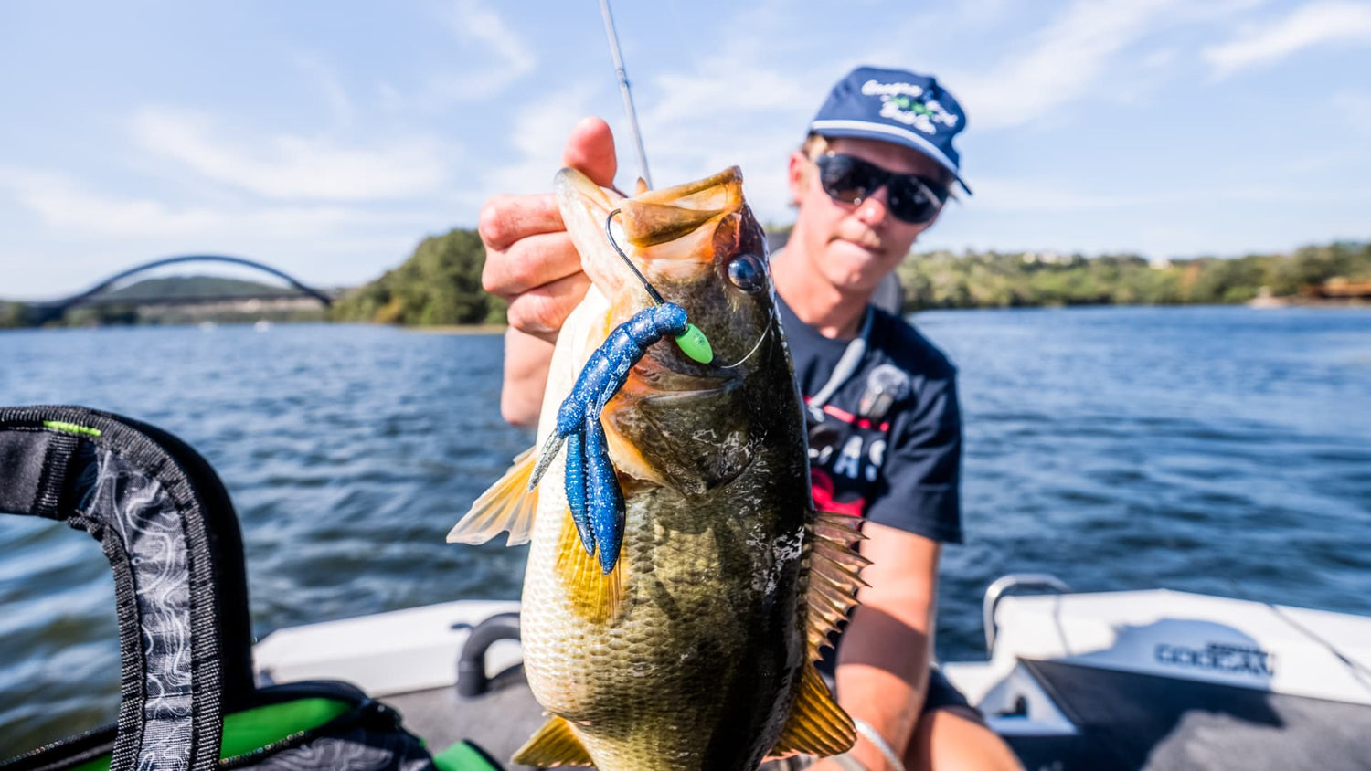 Angler holding bass caught on blue soft plastic bait on boat