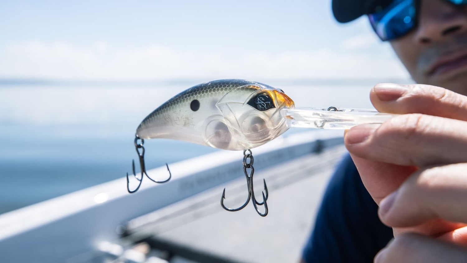 Close-up of an angler holding a squarebill crankbait on a boat.