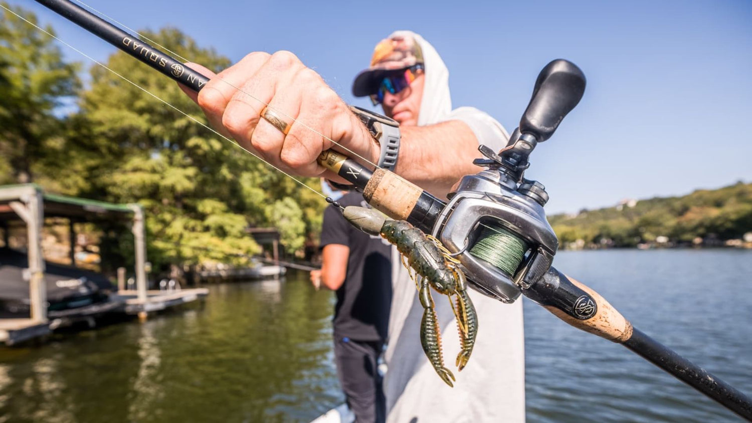 Texas rigged craw bait on baitcasting rod held over lake water