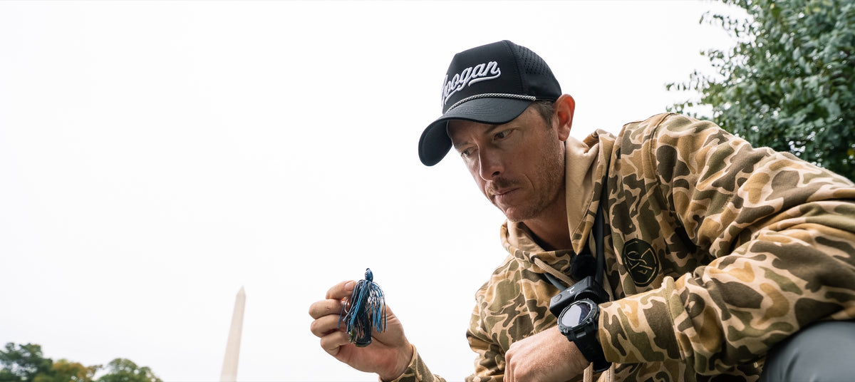 Angler in the tan camo Cast N' Catch Hoodie choosing a jig